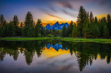 Sunset over Schwabacher Landing with Teton Mountain Range reflected in the waters of Snake River in Wyoming, USA. Long exposure.