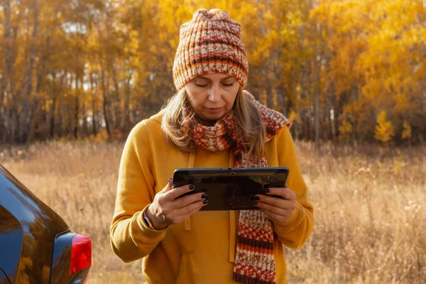 A woman uses a tablet on a car trip on vacation in the fall. A woman reads a guidebook map on a tablet computer using the mobile Internet