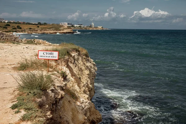 Rocky seashore. Landscape photography. Sea waves. Beautiful skies. A sharp break. The inscription on the sign \