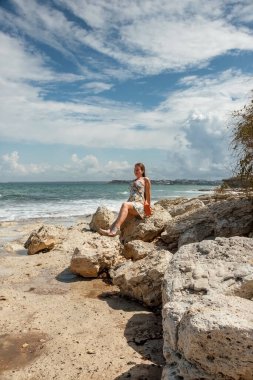 Deniz kıyısında yaz elbisesi giymiş bir kız. Güzel doğa. Kaya kıyısı. Yolculuk.