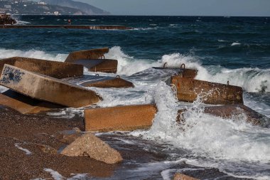 Beton tetrapodlarla erozyondan kıyıları güçlendirmek. Beton bloklu deniz kıyısı. Su elementi. Dalgalar betonda kırılır.