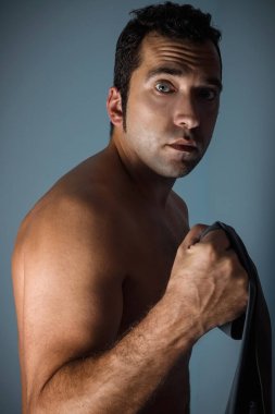 Bronzlaşmış bir adam evde antrenman yapıyor. Antrenman için genişletici. Pazı kasları için egzersiz..