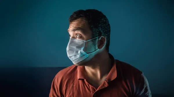 Ein Braun Gebrannter Mann Mit Medizinischer Maske Auf Blauem Grund — Stockfoto
