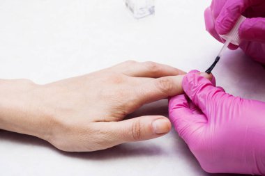 Manikürcü tırnakları cila ile kaplıyor. Tırnak bakımı fikri.