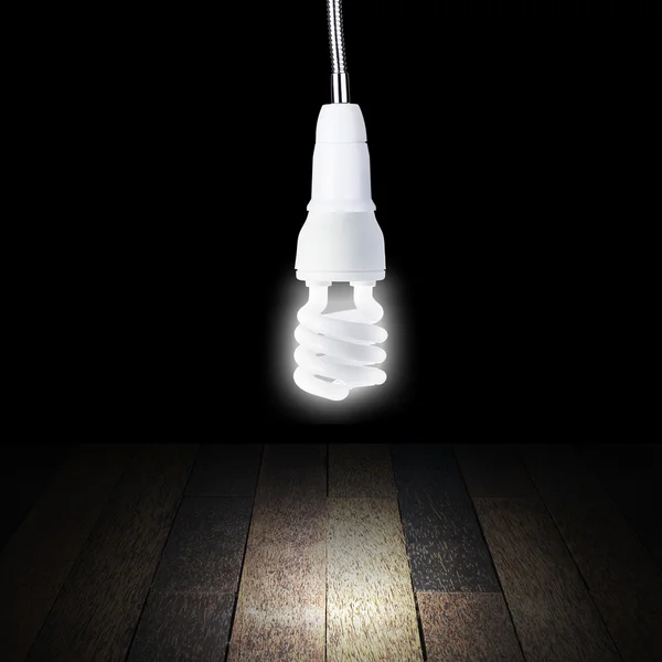 Glühbirne schaltet sich im leeren Raum mit Holzboden ein — Stockfoto