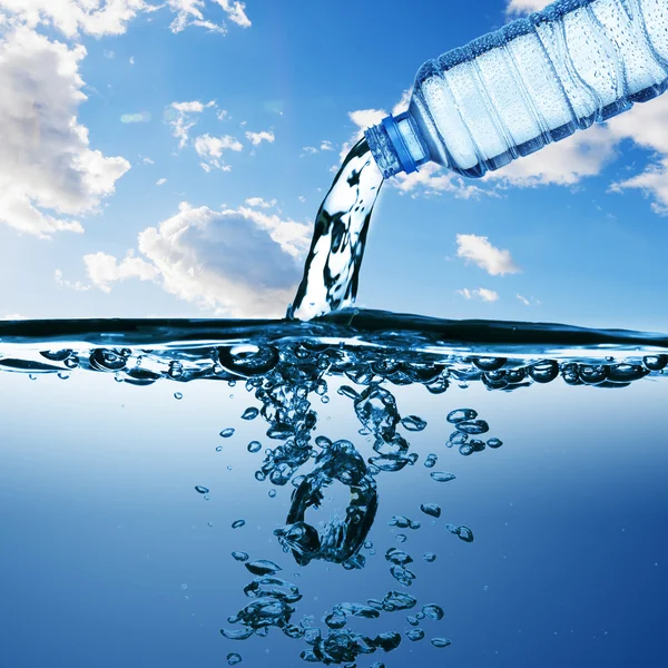 Agua de la botella de agua con burbuja formando sobre fondo azul — Foto de Stock