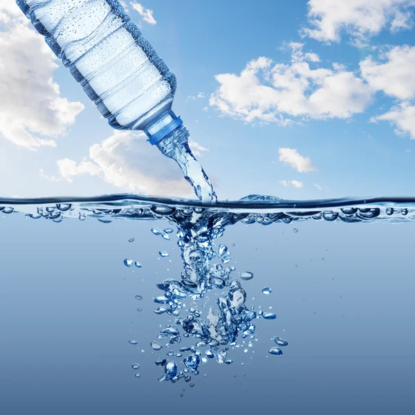 Acqua dalla bottiglia d'acqua con bolla che si forma su sfondo blu — Foto Stock