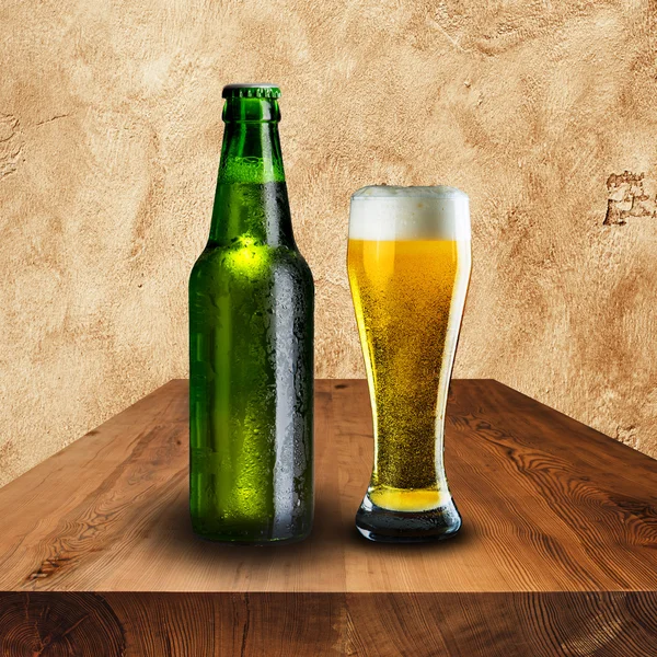 Bottle and glass of cold beer on wood table — Stock Photo, Image