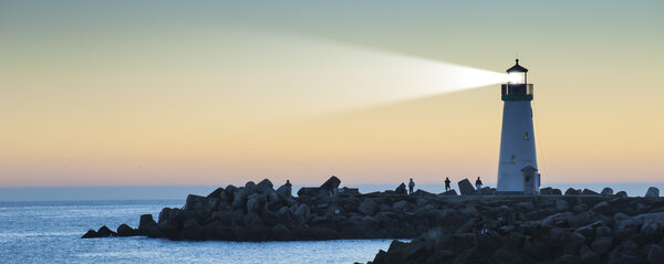 Lighthouse with light beam at sunset