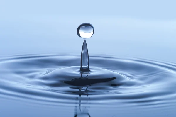 Gota de água na água azul — Fotografia de Stock