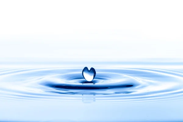 Vattendroppe på blått vatten — Stockfoto