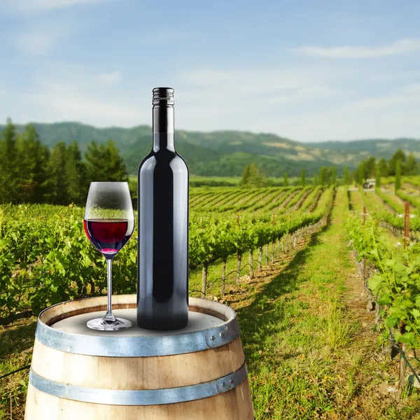 Glass and bottle of red wine on wood barrel — Stock Photo, Image