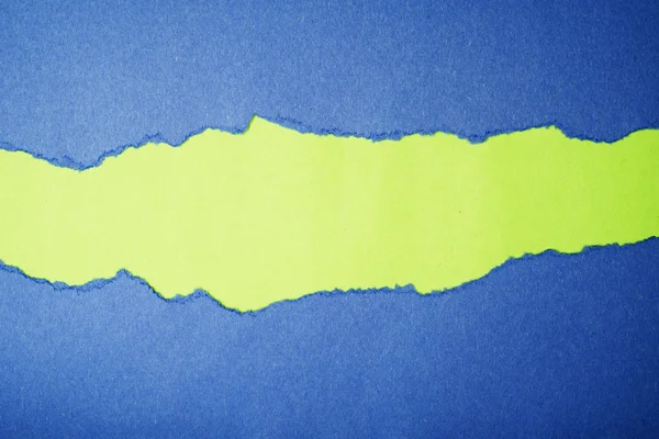 Torn blue color paper on green color background — Stock Photo, Image