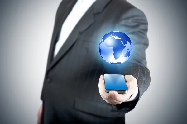 Бизнесмен держит мобильный телефон с глобусом — стоковое фото