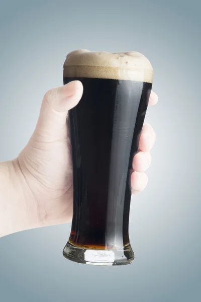 Hand holding glass of dark beer — Stock Photo, Image