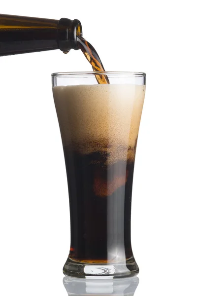 Cerveja escura derramando de garrafa para vidro — Fotografia de Stock