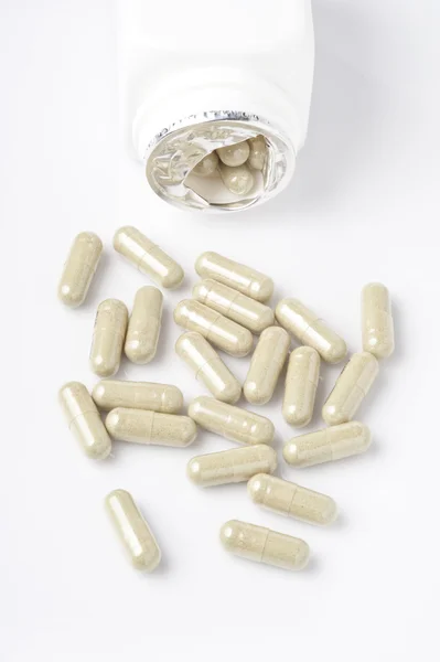 Capsules spilling out from small bottle — Stock Photo, Image