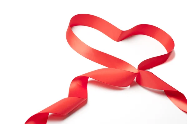 Красная атласная лента, формирующая форму сердца — стоковое фото