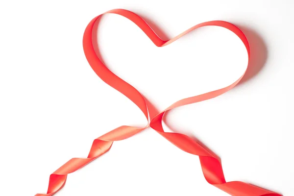 Красная атласная лента, формирующая форму сердца — стоковое фото