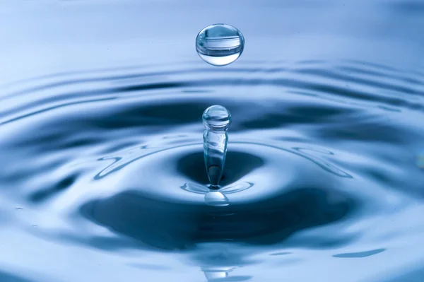 Капля воды на голубой воде — стоковое фото
