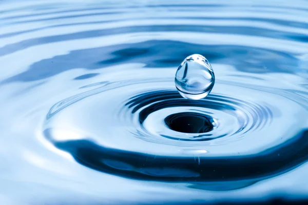 Gota de água na água azul — Fotografia de Stock