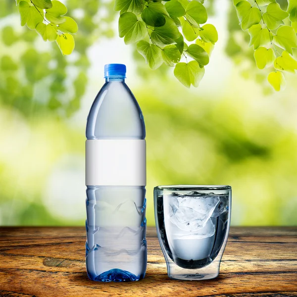 Flasche und Glas Wasser auf Holztisch — Stockfoto