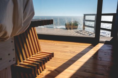 Okyanusun önünde güneş ışığı ve güzel mavi gökyüzü olan güzel ahşap teras.