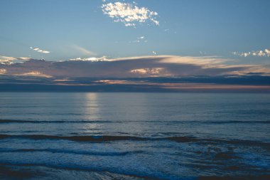 Pasifik Okyanusu 'nun panoramik manzarası ve ufukta güzel bir gün batımı bulutların arkasında güneş ve sahil ve deniz.
