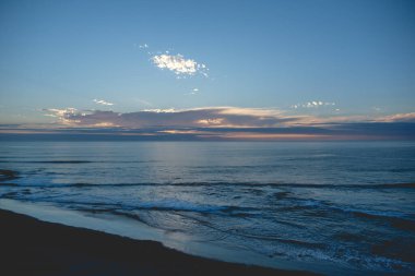 Pasifik Okyanusu 'nun panoramik manzarası ve ufukta güzel bir gün batımı bulutların arkasında güneş ve sahil ve deniz.