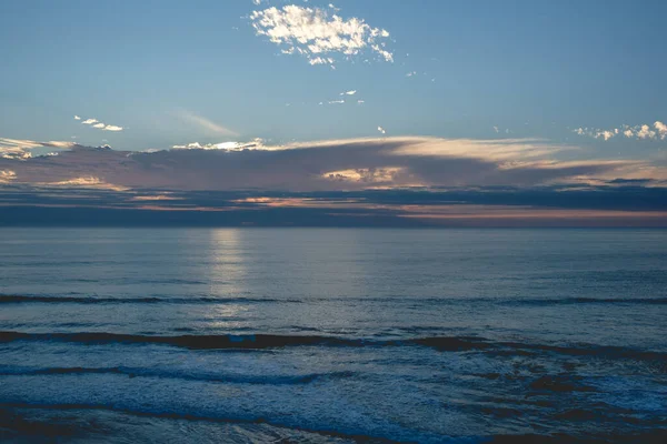 Pasifik Okyanusu 'nun panoramik manzarası ve ufukta güzel bir gün batımı bulutların arkasında güneş ve sahil ve deniz.