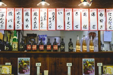 Osaka, Japonya: Aşçı, Shinsekai bölgesindeki geleneksel restoranda menüler, şişeler dolusu sake ve Japon içkisi asıyor 