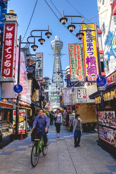 大阪府大阪市 通天閣 レストラン ふぐランプ 色と人自転車で新世界地区の通りを歩く — ストック写真