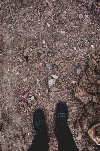 Füße Mit Schwarzen Turnschuhen Und Schwarzen Jeans Stehen Über Schmutzboden — Stockfoto