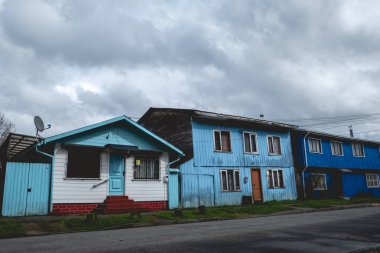 Mavi ve gökyüzü mavisi renkleri olan güzel ahşap evler, ve şaşırtıcı bulutlu gökyüzü, Valdivia, Şili