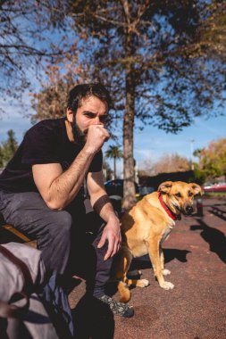 Formda ve yakışıklı atletik bir adam güneşli bir günde, güzel Alman çoban köpeği ile spor salonunda dinleniyor.