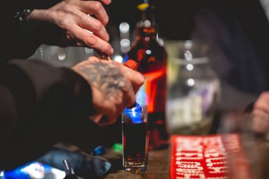 Barmen elleri biraz 'alevli doktor biberi' hazırlıyor. Amparetto ve aperatiften yapılan geleneksel bir kokteyl. Ateşe veriliyor ve birayla birlikte bardağa atılıyor.