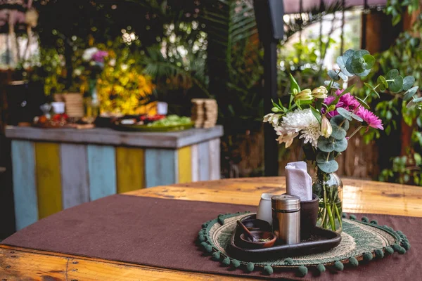 水に花の装飾が施されたボトル付きの木製テーブル ドレッシング 庭の結婚式パーティーの背景にあるテーブルでカラフルなビーガンケータリング — ストック写真