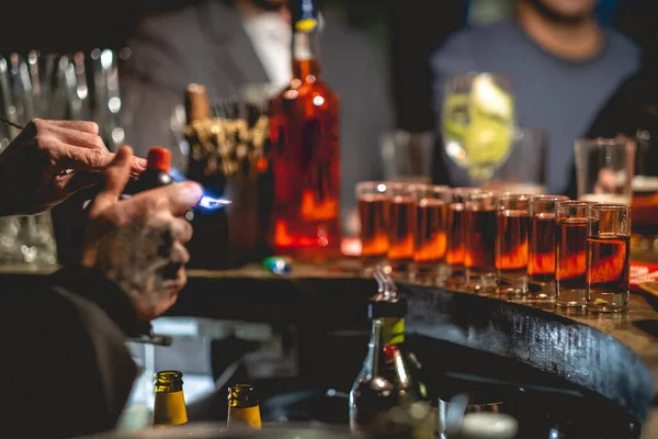 Barmen elleri biraz 'alevli doktor biberi' hazırlıyor. Amparetto ve aperatiften yapılan geleneksel bir kokteyl. Ateşe veriliyor ve birayla birlikte bardağa atılıyor.