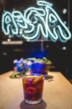 'Area' Kafe 'de portakallı soğuk kahve bardağı, gece yeşil süslemeli bitki ve gece mavi ışıklı ve neon ışıklı.