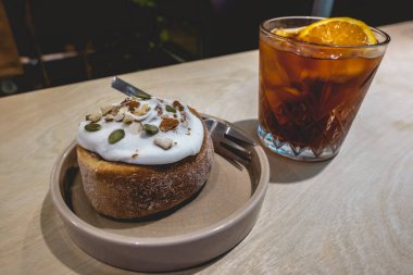 İçi portakallı soğuk kahve ve nefis tarçınlı kek bir kahve dükkanının içindeki ahşap masanın üzerinde.