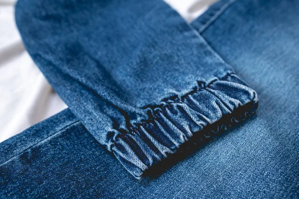 Leg detail of fashion blue jeans over wrinkled white sheet