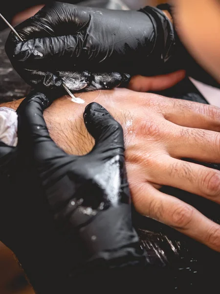 黒手袋のタトゥーアーティストの手の詳細伝統的な日本の 手ポーク 技術を持つ男の手の中に陰陽の白い色合いと新しい入れ墨を作る — ストック写真