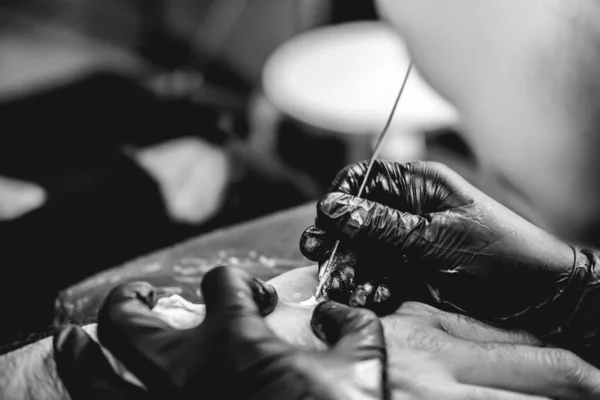 黒手袋のタトゥーアーティストの手の詳細伝統的な日本の 手突き 技術を持つ男の手の中に陰陽の白い色合いの新しい入れ墨を作る 黒と白で — ストック写真