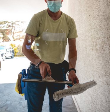Gündüzleri büyük cam temizleme aletleriyle maske takan temizlikçi adam.