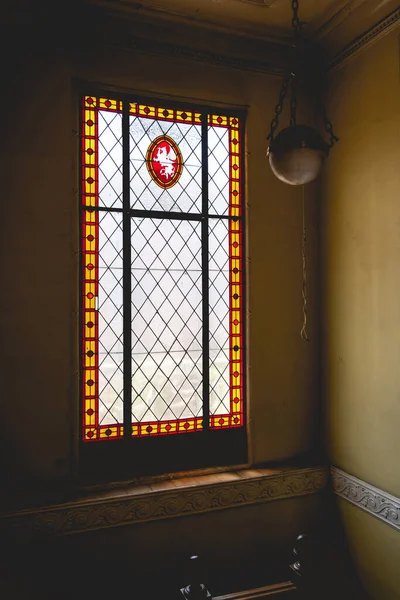 龍と装飾と古いぶら下げランプと腕のコートとカラフルなアンティークステンドグラスの大きな窓 — ストック写真