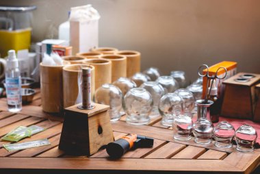 Çin sigara kutusunda bitkisel moxa çubuğu olan ahşap masa, kap kacak için cam bardaklar, otlar, pamuk ve diğer tıbbi malzemeler.