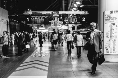 Osaka, Japonya: Tren raylarında gezginler bekliyor ve yürüyor (siyah ve beyaz))