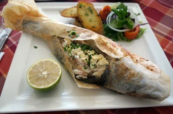 parşömen üzerine beyaz bir tabak içinde pişmiş levrek