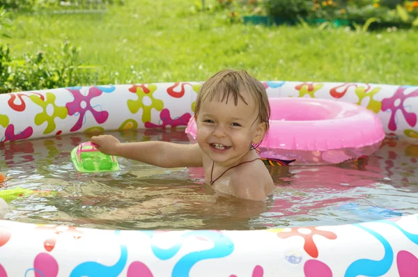 Twee-jaar-oude meisje baadt in opblaasbare kinderbad en lacht Stockafbeelding