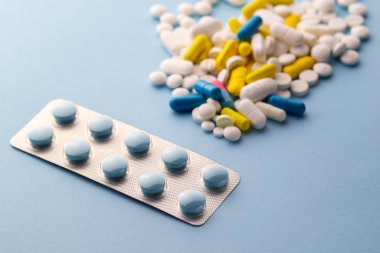 Aşırı dozda hap. İlaçlar. Çok renkli haplar ve ilaçlar. İlaçların geçmişi. Grip tedavisi. Coronavirus tedavisi. Eczane. Kamu alanındaki ilaçlar. Vitaminler. - Uyuşturucu. Mavi arka planda renkli terlikler. Soğuk algınlığı tedavisi